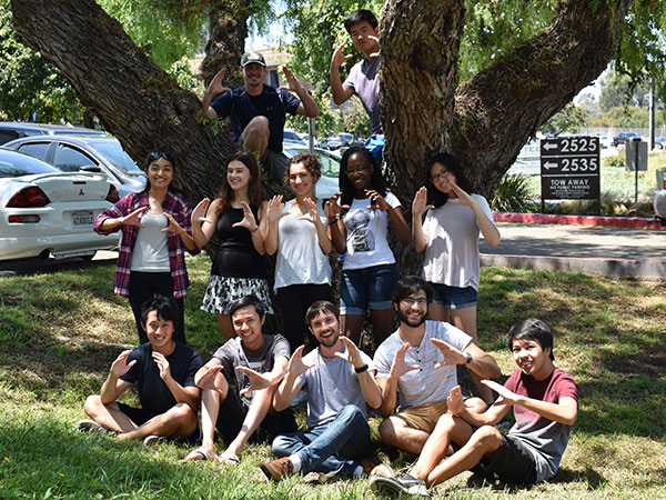 Summer coding camp leaders having fun outdoors around tree